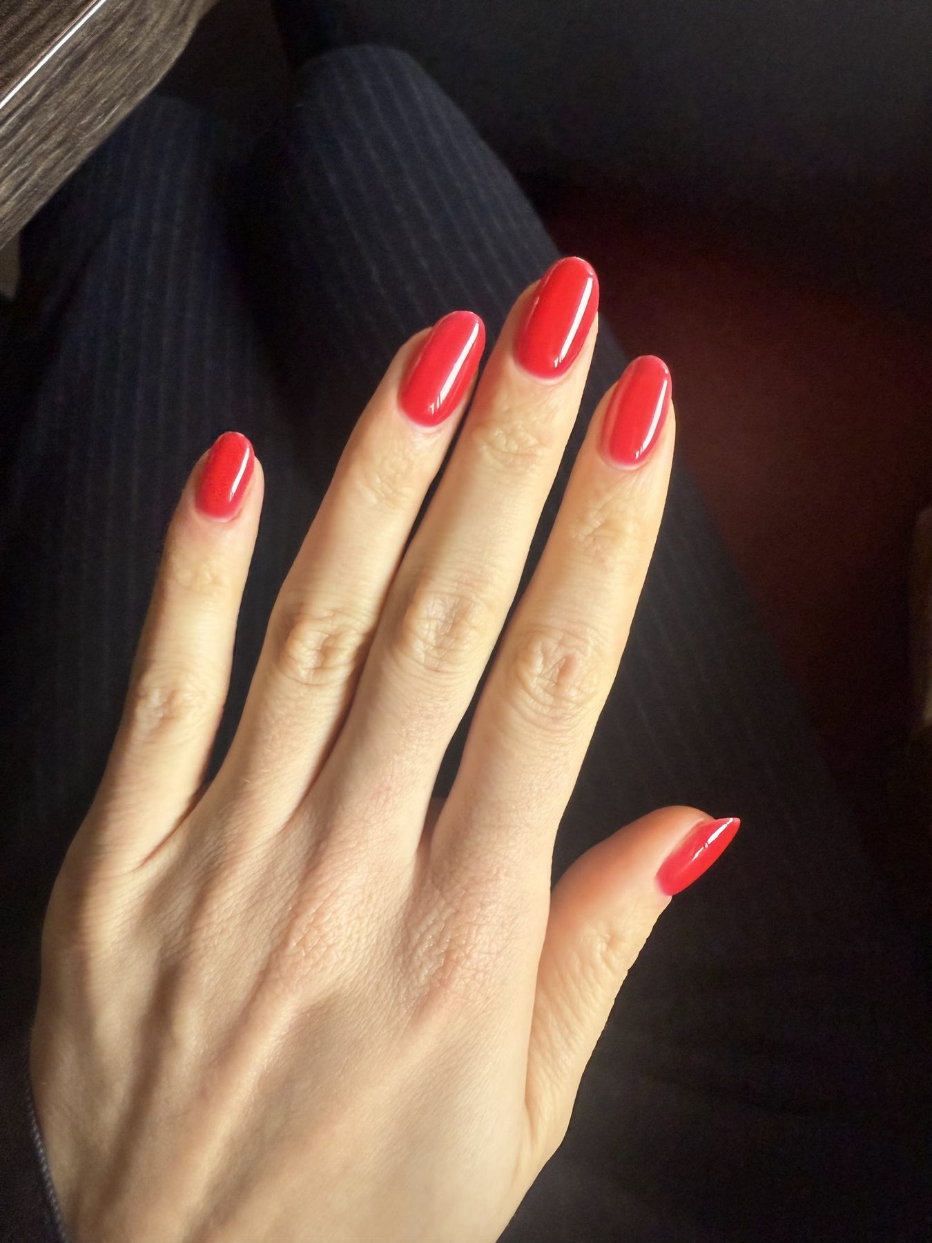 Een hand met glanzend rode, amandelvormige nagels
