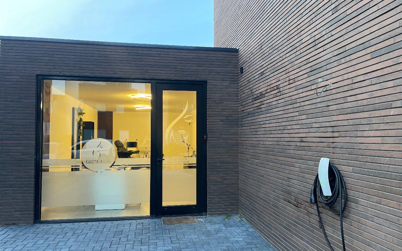 De ingang van Glow Hub met het geëtste gezicht op het glas, 's avonds verlicht